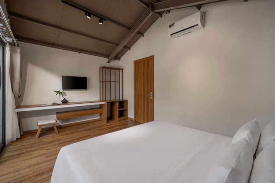 The vaulted ceiling and the walnut wardrobe — bedroom one at Fuka House, Da Nang