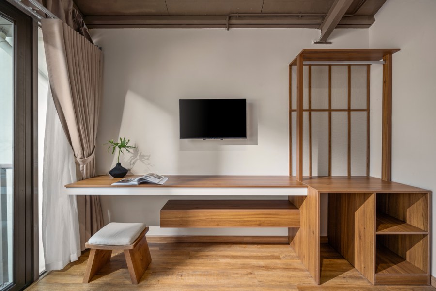 A floating desk and shelf below the television — bedroom one at Fuka House, Da Nang