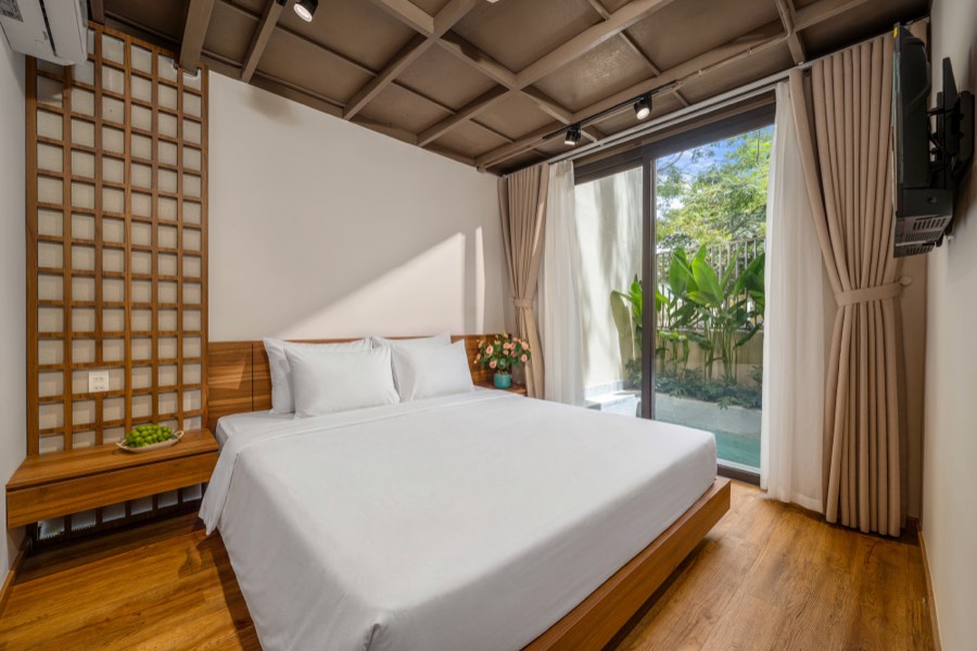 Bedroom Three — a king bed with a lattice screen and glass doors onto the pool