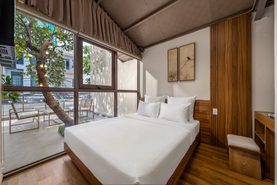 Bedroom Two — a king bed beside glass doors opening onto the terrace tree