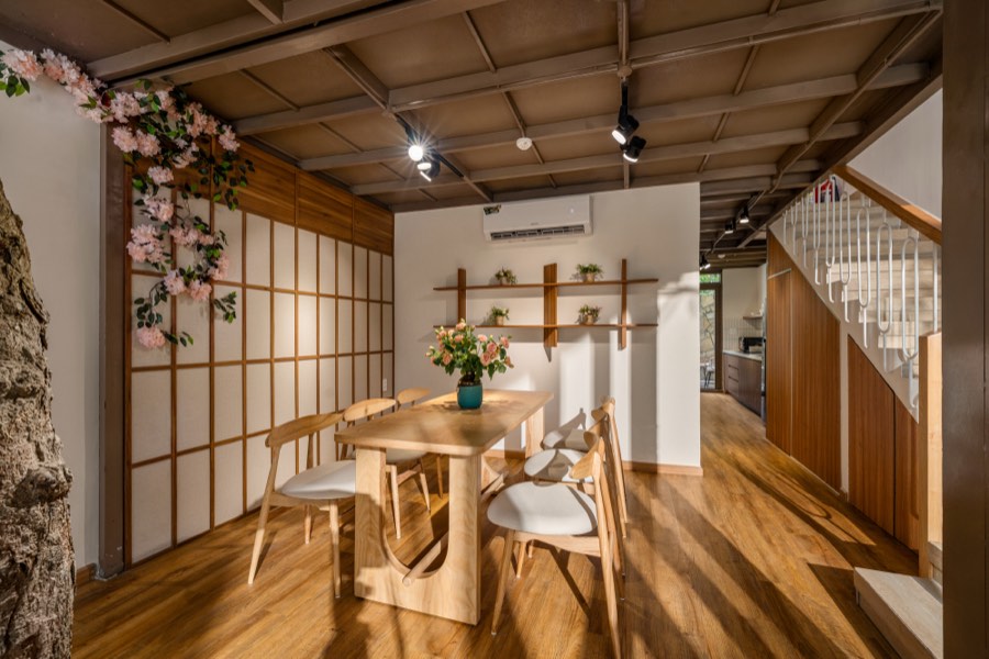 Paper screens and blossom along the dining-room wall — dining room at Fuka House, Da Nang