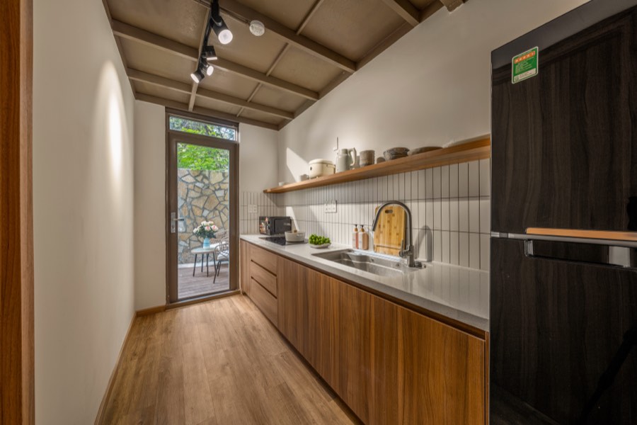 Galley kitchen in walnut with a stone counter and a door to the garden