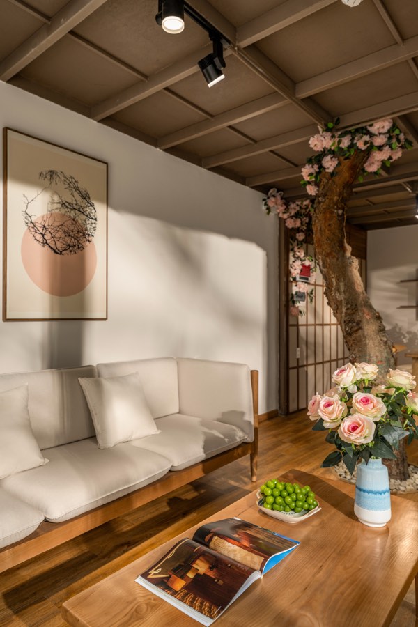 Living room sofa below a framed sun print, with blossom overhead