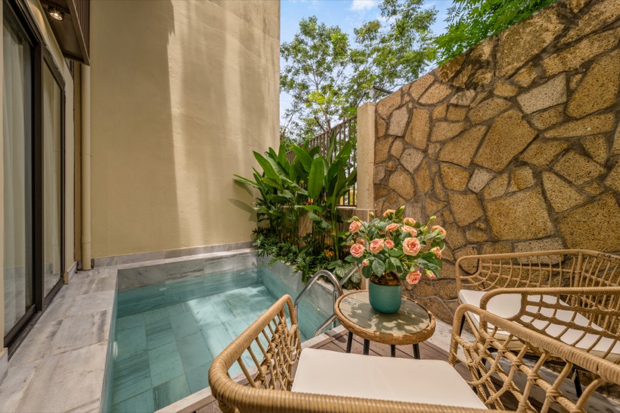 The private pool in its courtyard, with rattan chairs beside a stone wall