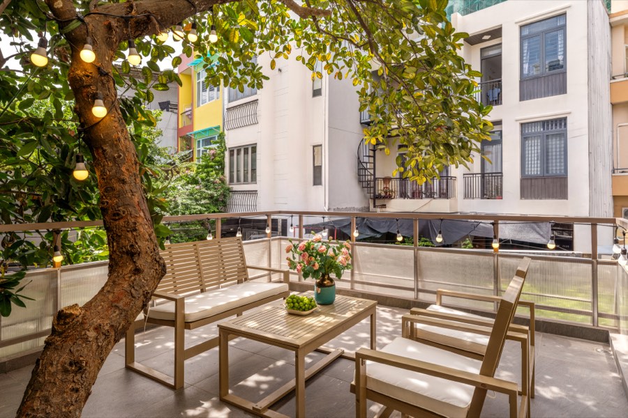 The first-floor terrace with garden furniture under the branches of a large tree