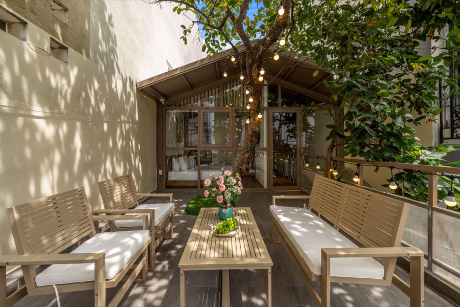 Seating in the shade of the terrace tree, lanterns strung through the branches